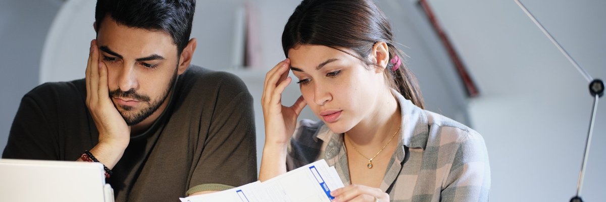 A young couple sadly looking through bills.