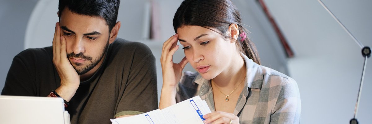 A young couple sadly looking through bills.