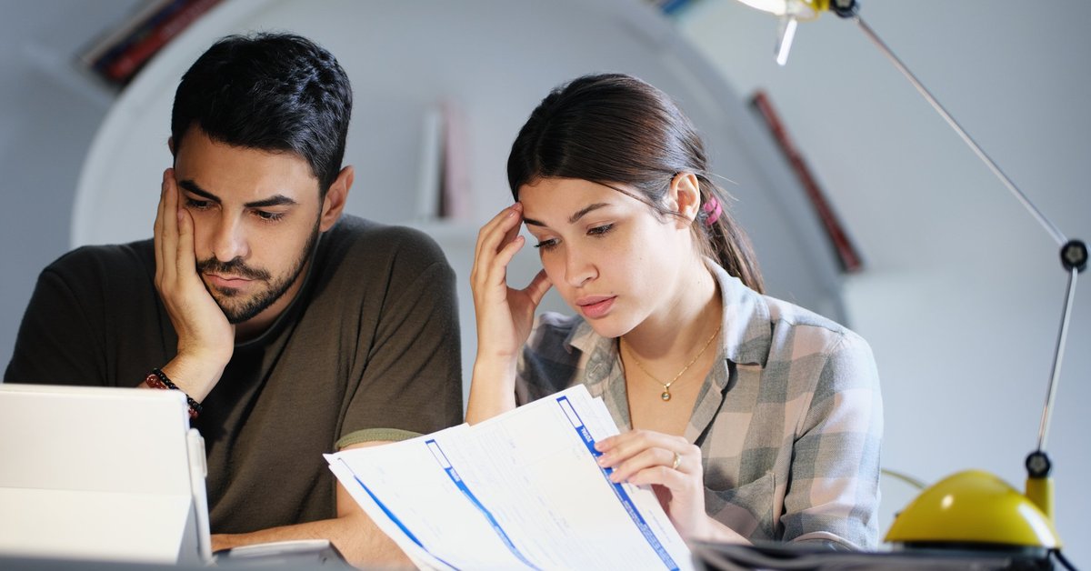 A young couple sadly looking through bills.
