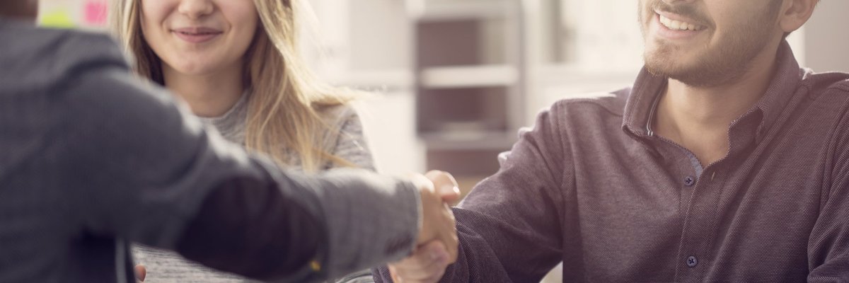 A young couple shaking hands with a bank employee.