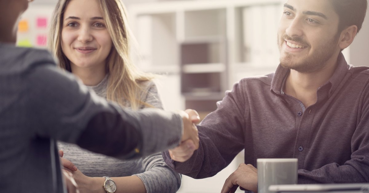 A young couple shaking hands with a bank employee.