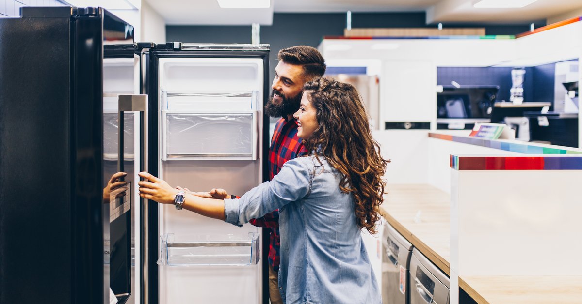 A young couple shopping for a new refrigerator at an appliance store.