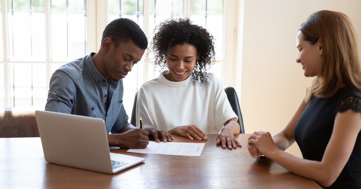 Young couple signing papers with an agent.