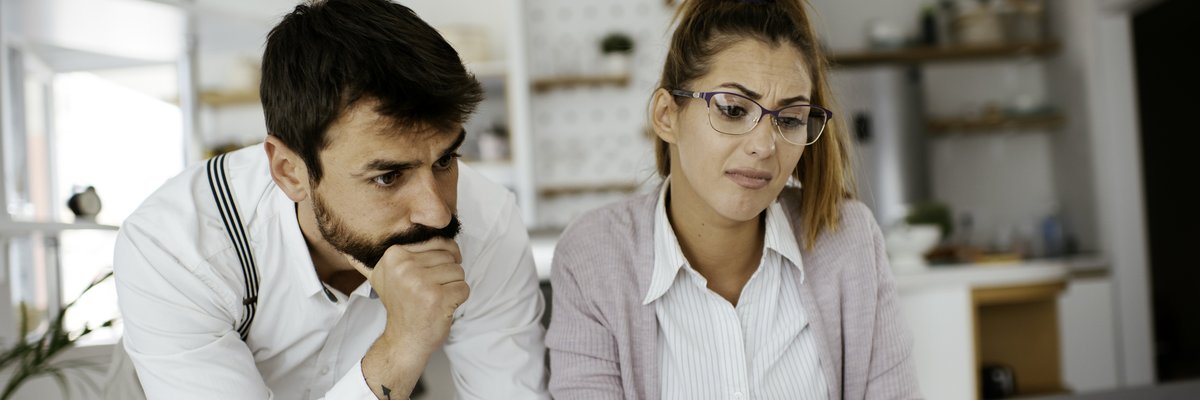 Young couple skeptically looks at information on a laptop screen