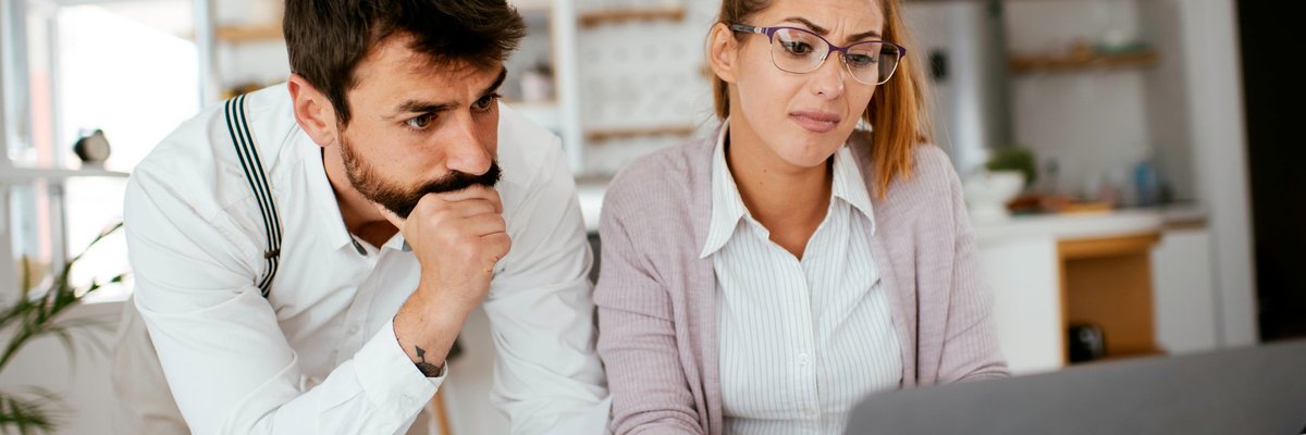 Young couple skeptically looks at information on a laptop screen