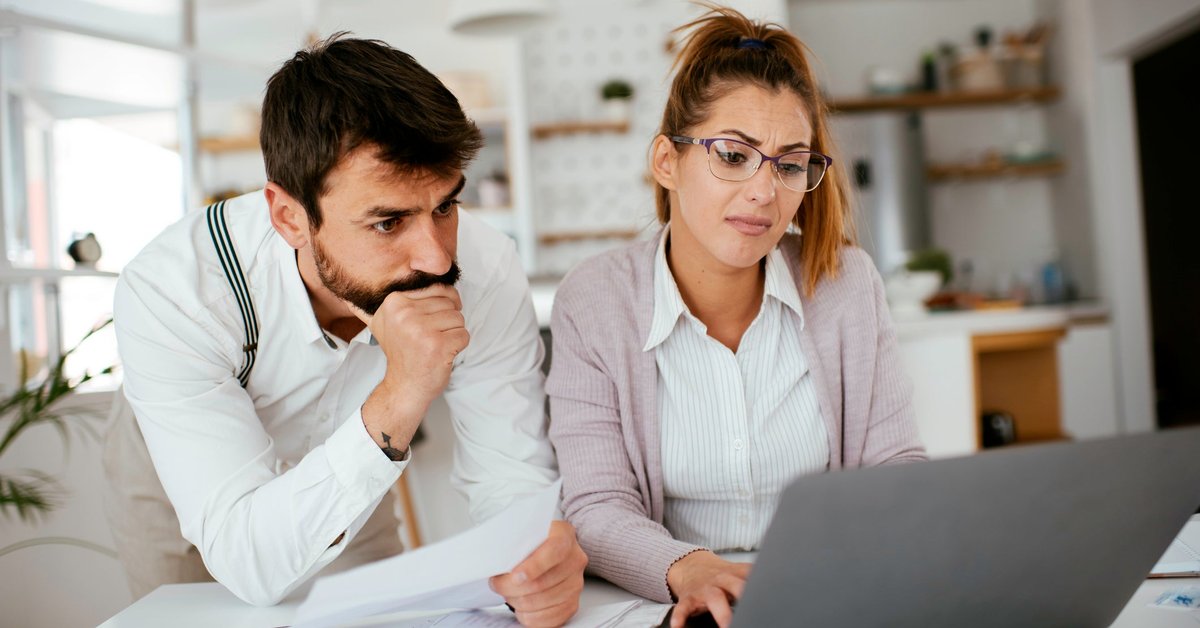 Young couple skeptically looks at information on a laptop screen