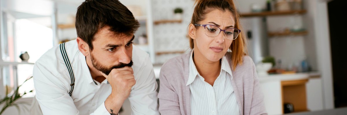 Young couple skeptically looks at information on a laptop screen