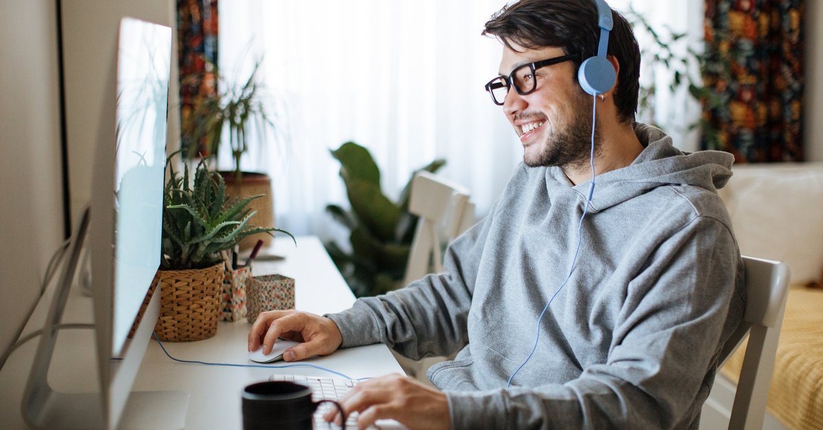 A young daytrader sits at his desk at home, looking at his computer.