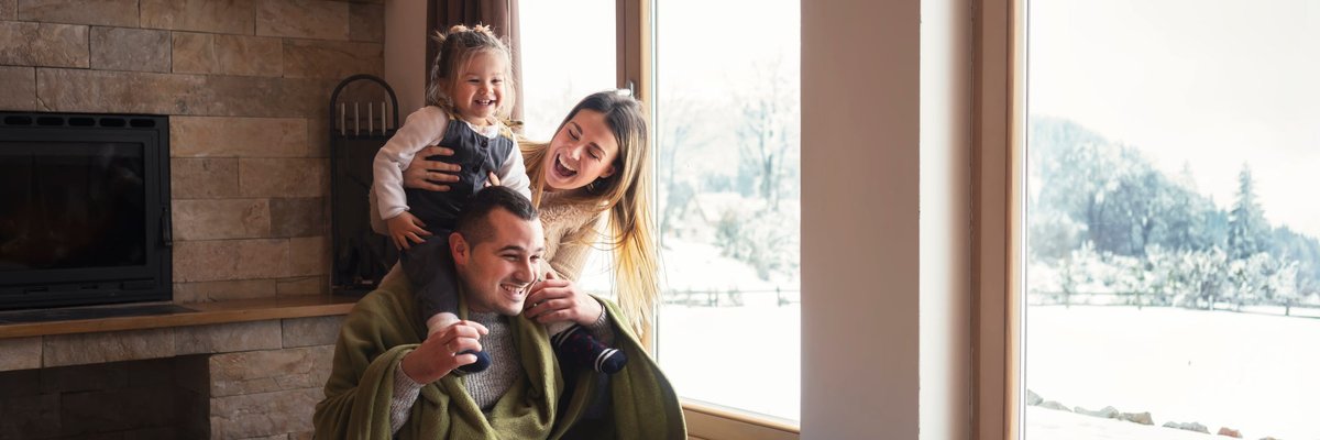 Young family bundled up in warm clothes by a window.