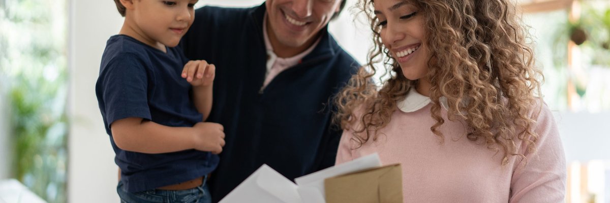 Young family smiles while looking through mail.