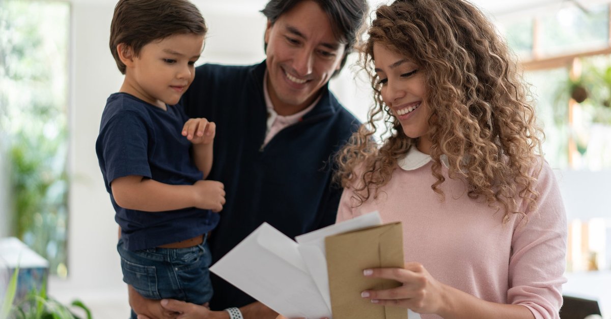 Young family smiles while looking through mail.