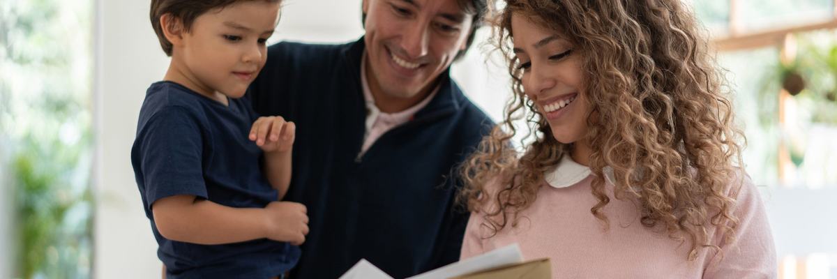 Young family smiles while looking through mail.