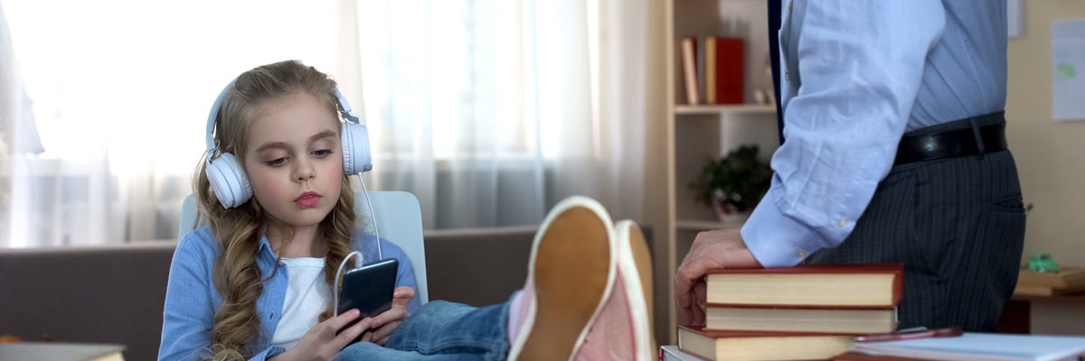 A young girl wearing headphones while ignoring her dad.