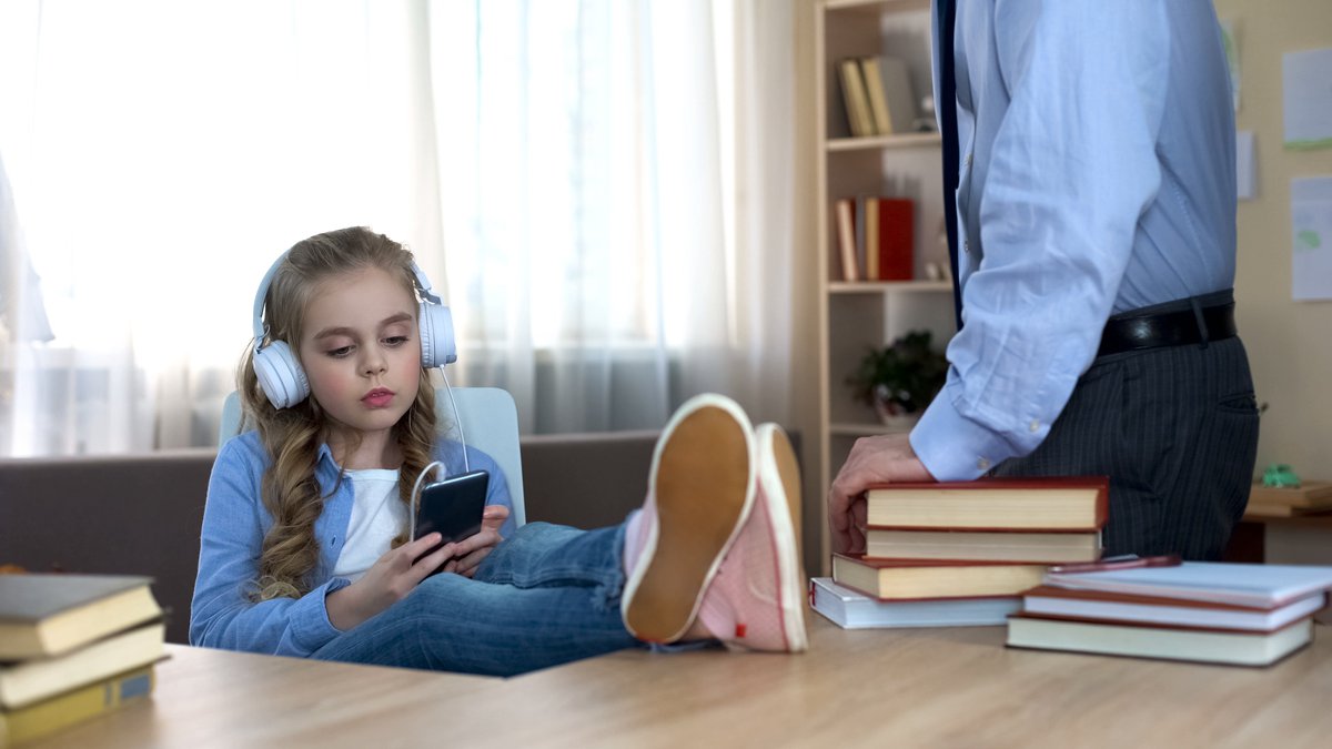 A young girl wearing headphones while ignoring her dad.