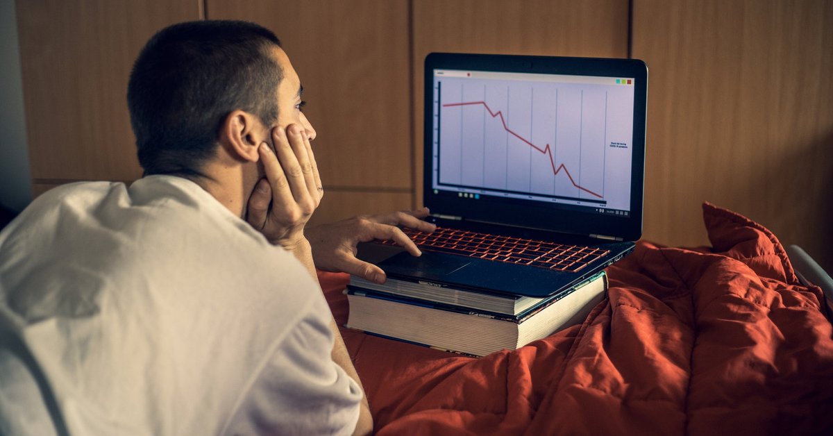 Young man looking at downward trending data on his laptop