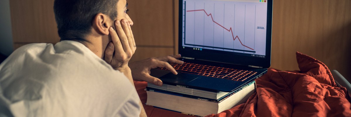Young man looking at downward trending data on his laptop