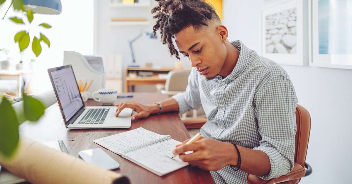 A young man sits at his desk and looks over his investment accounts.