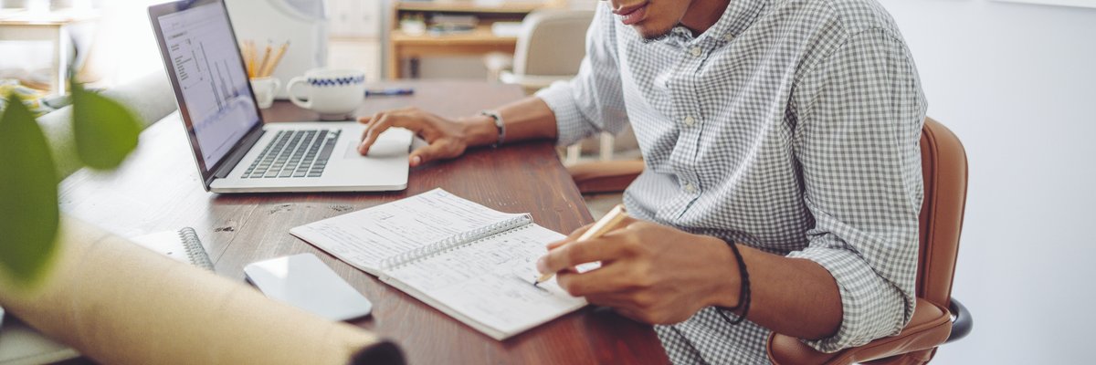 A young man sits at his desk and looks over his investment accounts.