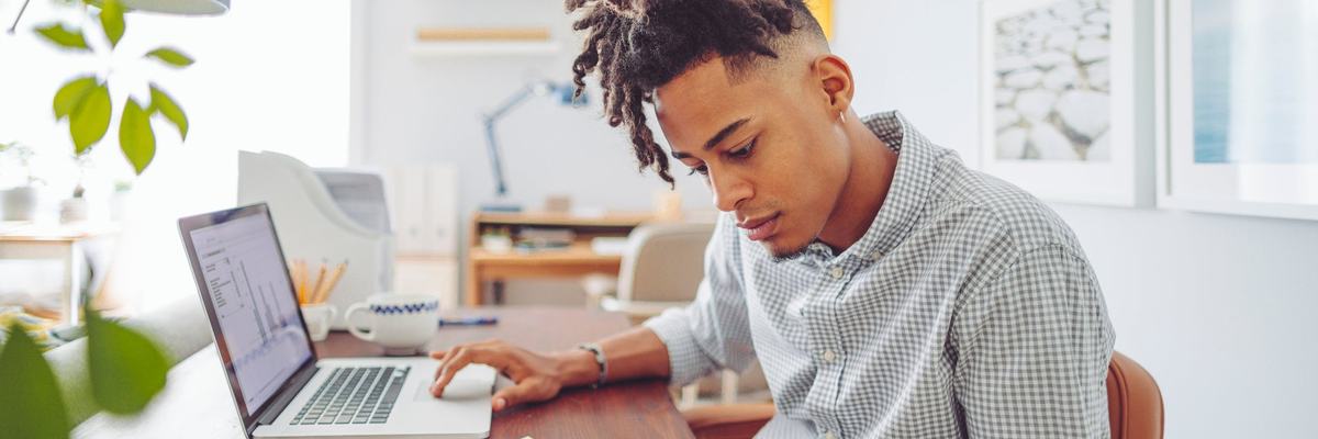 A young man sits at his desk and looks over his investment accounts.