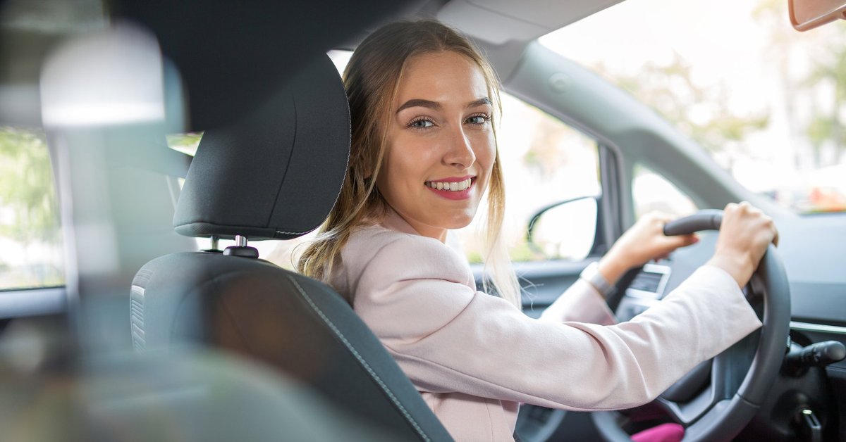 Young woman driving car and smiling