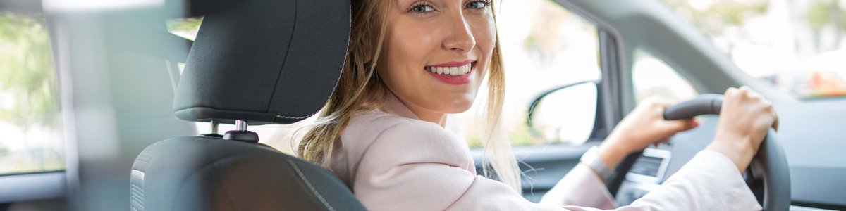 Young woman driving car and smiling