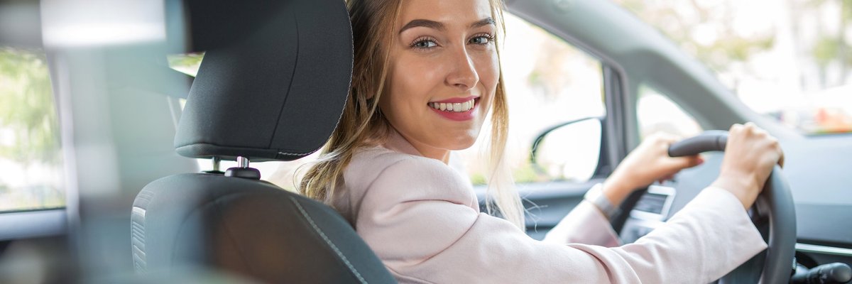 Young woman driving car and smiling