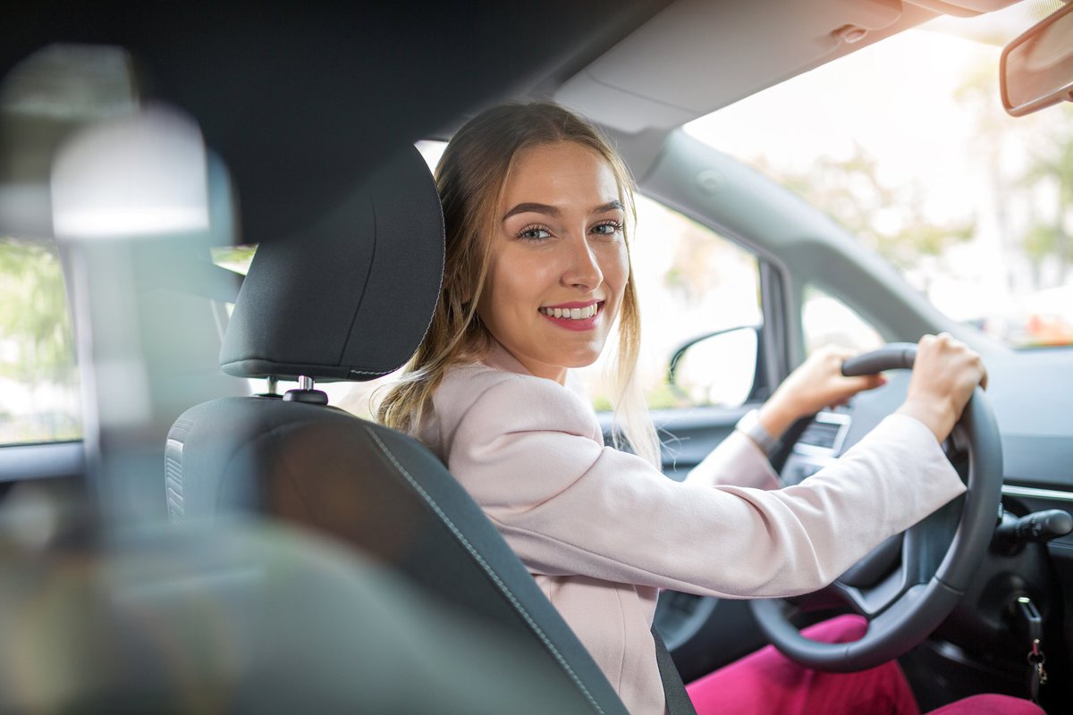Young woman driving car and smiling