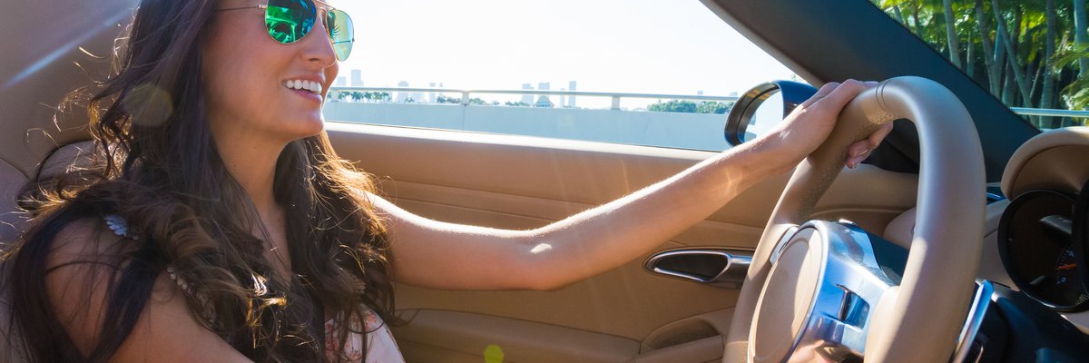 Young woman driving convertible near the coast.