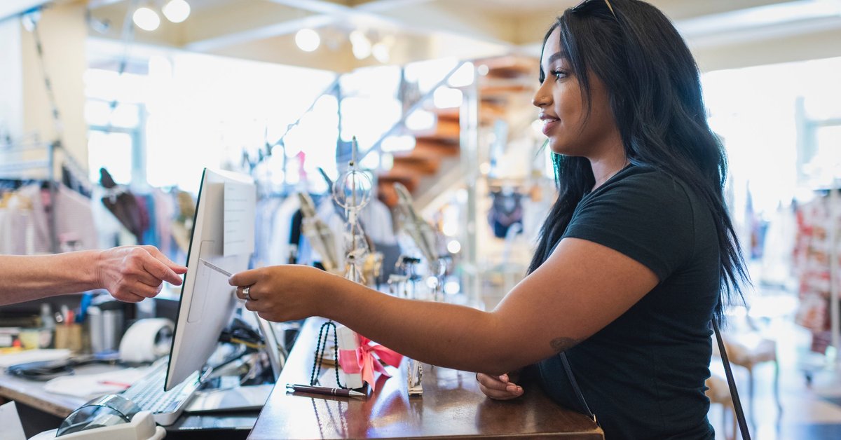 Young woman paying cashier with credit card in a clothing store