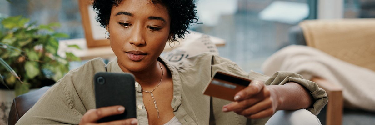 A young woman sits and makes an online purchase, which she pays for with her credit card.
