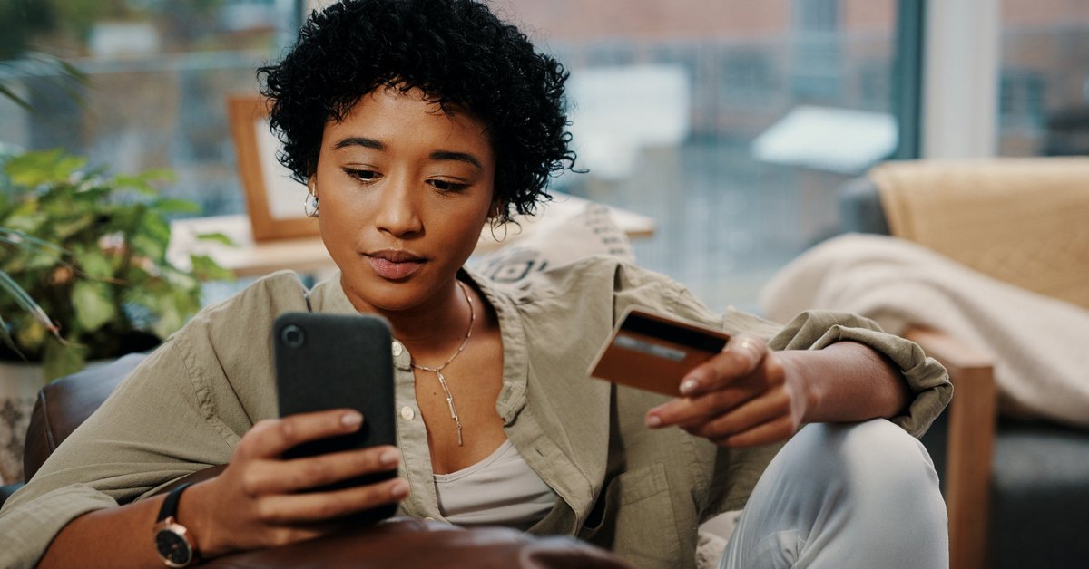 A young woman sits and makes an online purchase, which she pays for with her credit card.