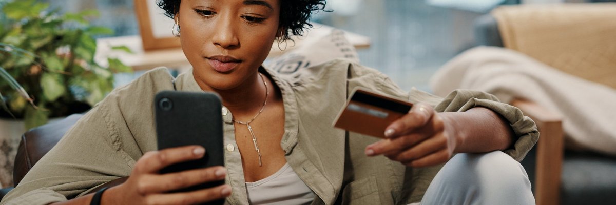 A young woman sits and makes an online purchase, which she pays for with her credit card.