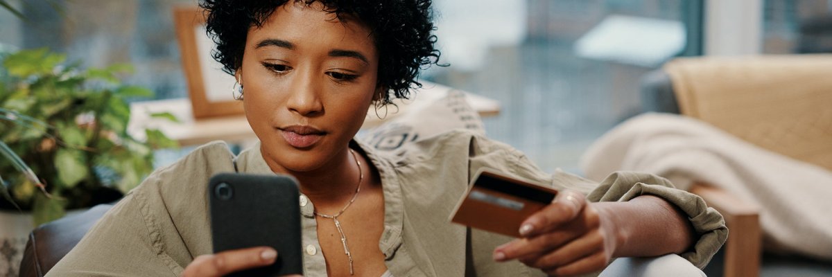 A young woman sits and makes an online purchase, which she pays for with her credit card.