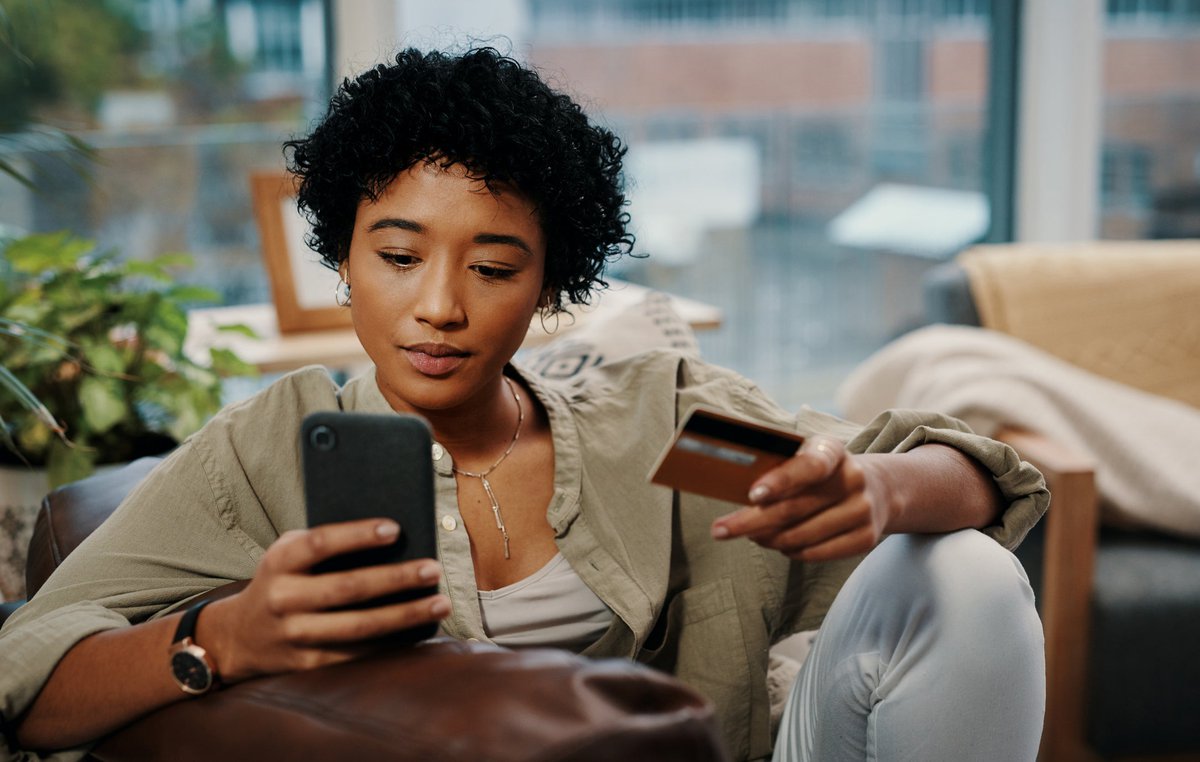 A young woman sits and makes an online purchase, which she pays for with her credit card.