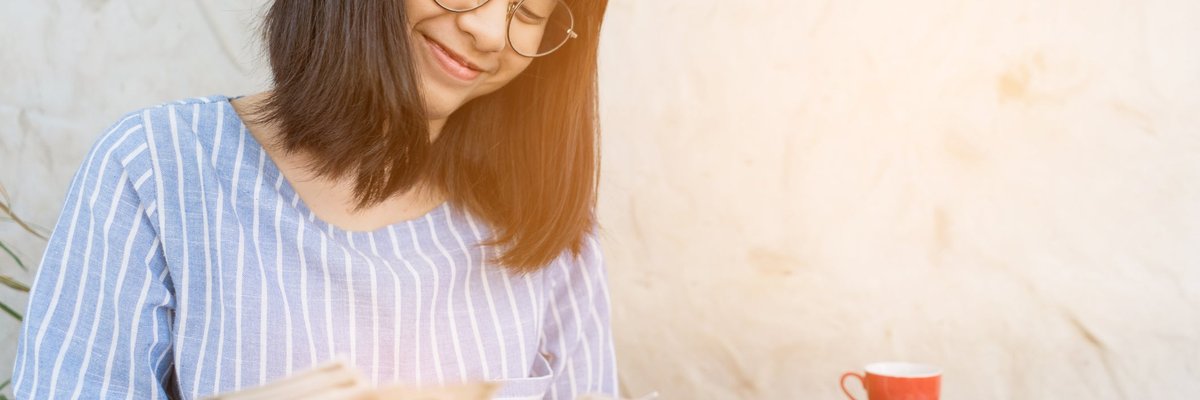 Young woman smiling as she counts cash in her hands.