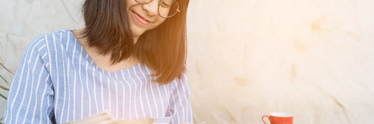 Young woman smiling as she counts cash in her hands.