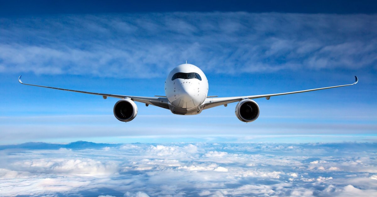 head-on shot of airplane flying high above the clouds