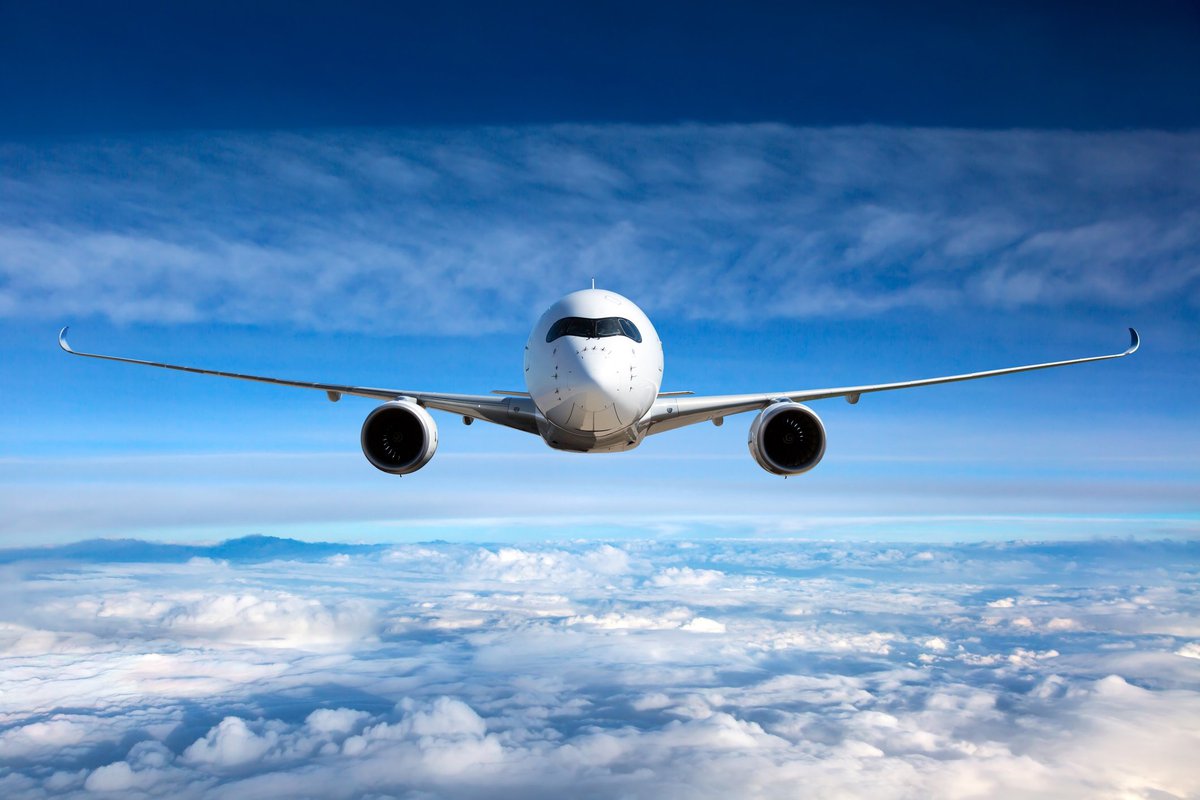 head-on shot of airplane flying high above the clouds