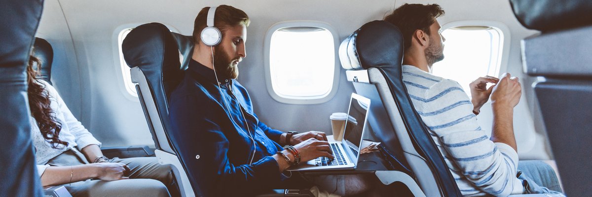 Three people sitting in consecutive aisle seats on an airplane.