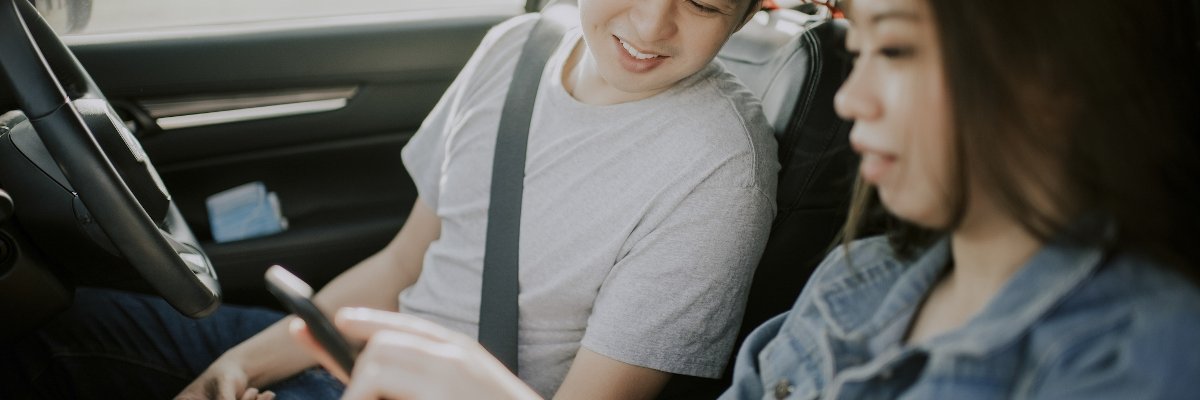 Young couple looking at phone in car.