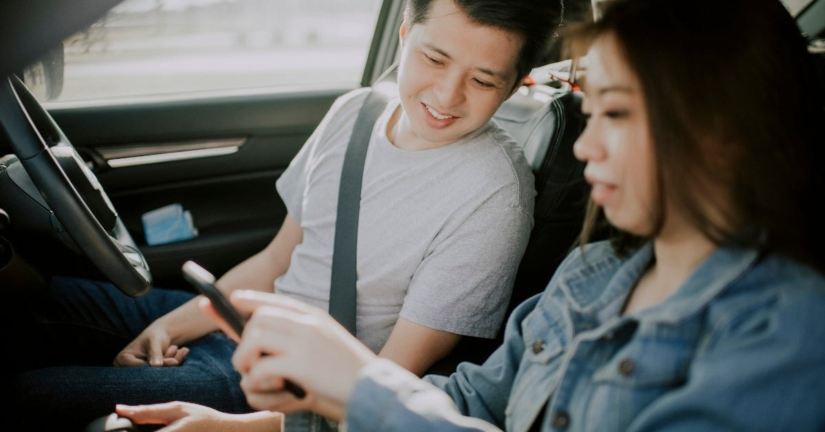 Young couple looking at phone in car.