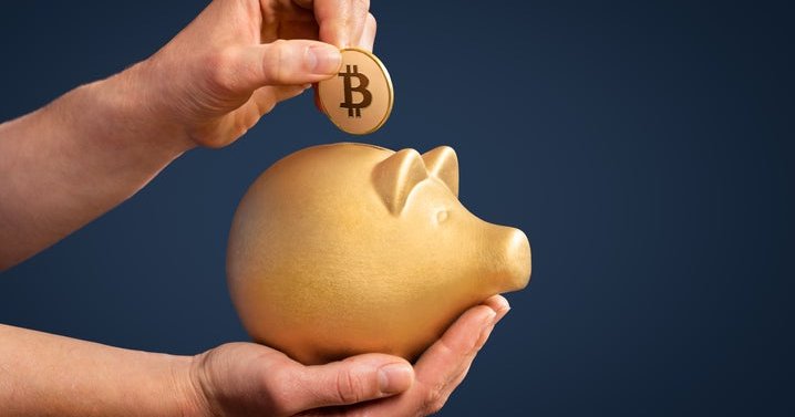 Hands holding a gold piggy bank and a gold Bitcoin above it.