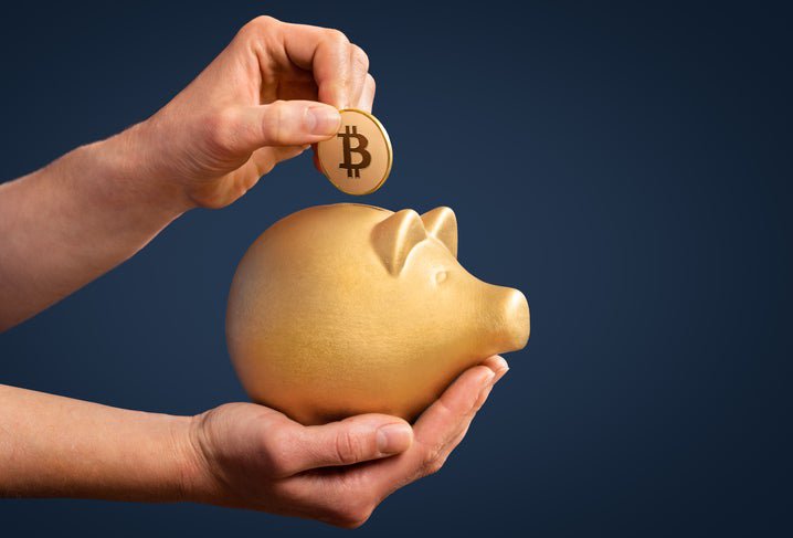 Hands holding a gold piggy bank and a gold Bitcoin above it.