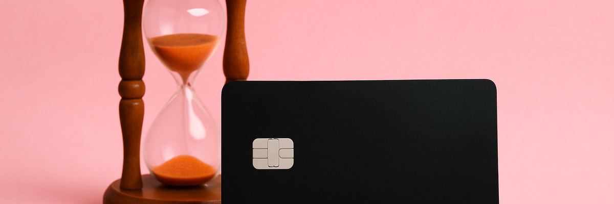 A black credit card and hourglass against pink background.