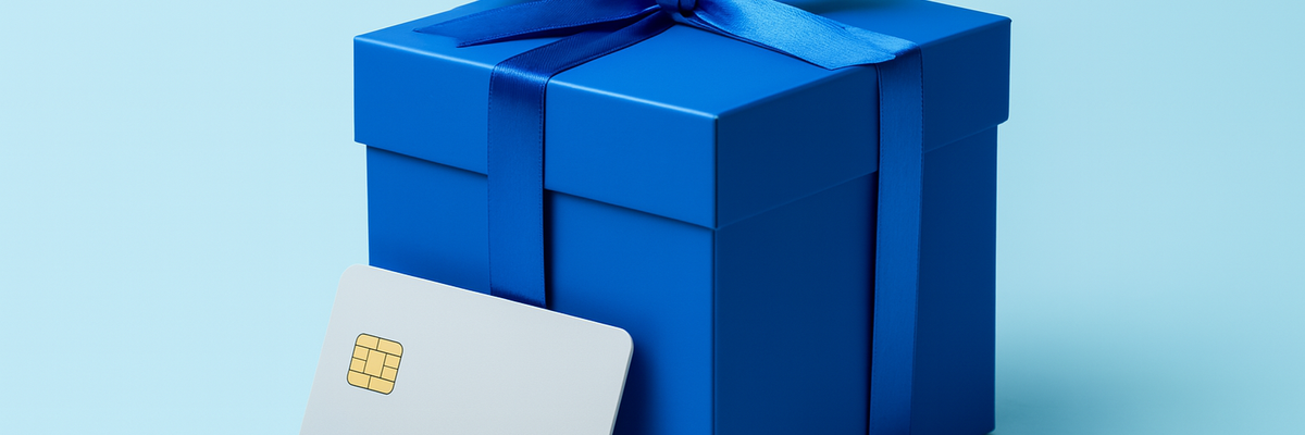 A blue gift box with white credit card leaning on it light blue background.