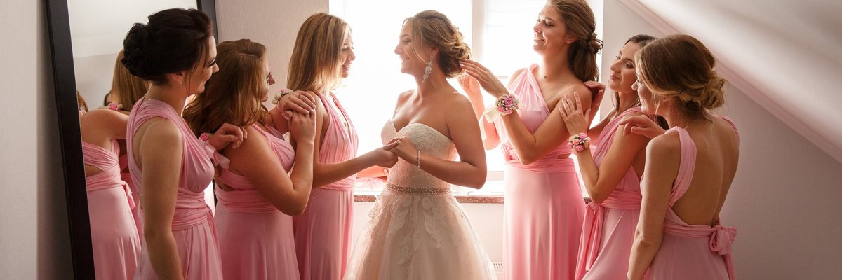 Group of women in pink dresses fawning over a bride