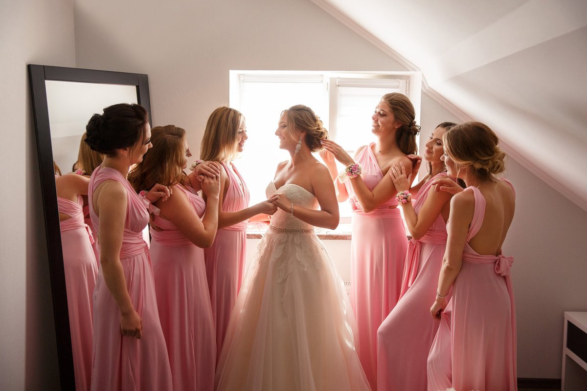 Group of women in pink dresses fawning over a bride