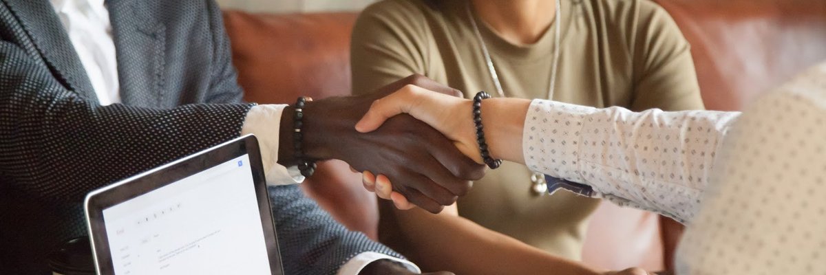 Smiling couple shaking hands with someone over a laptop