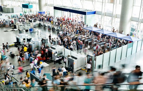 A busy airport security entrance with lots of people rushing through.