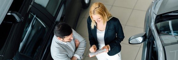 Man talking to woman at car dealership.